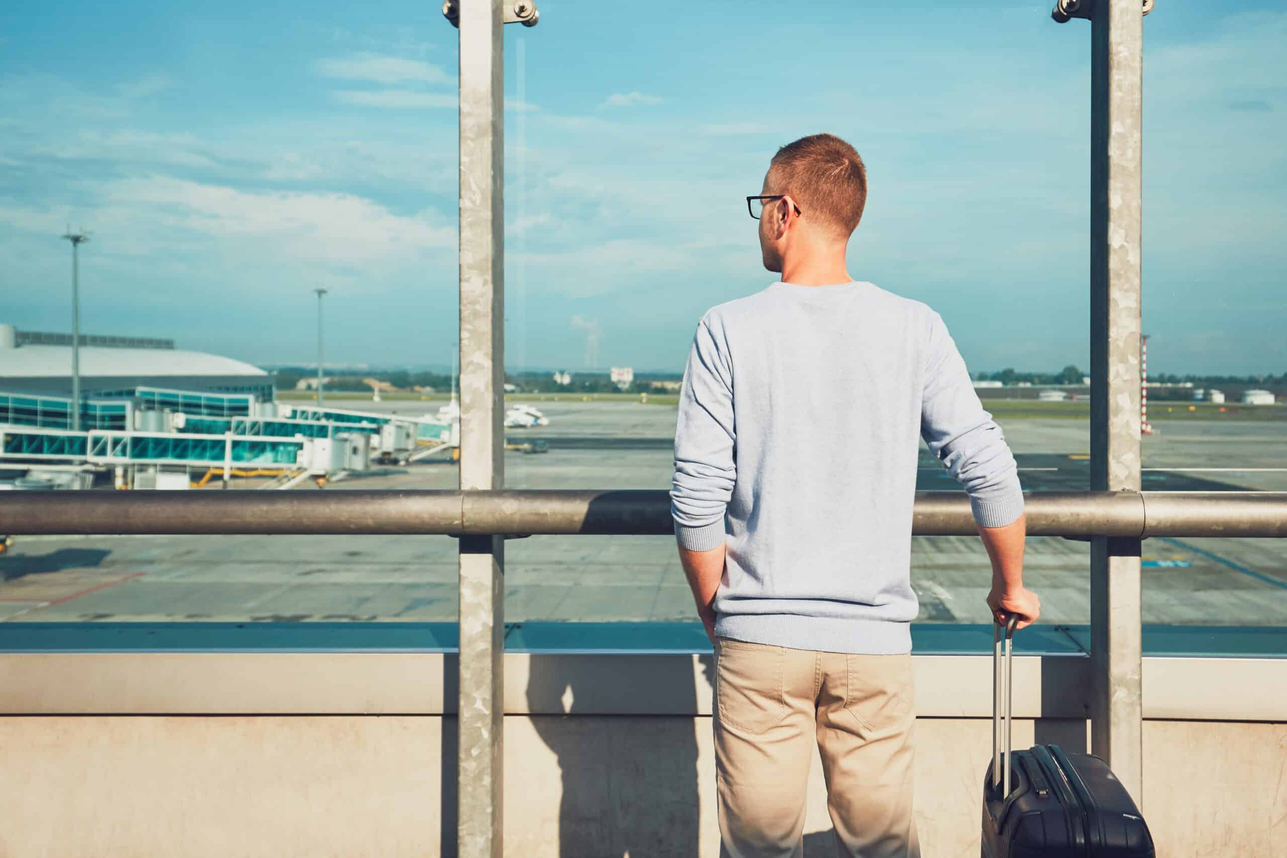 Traveler waiting for departure Man traveling by airplane. Young passenger waiting at the airport for a delayed flight.